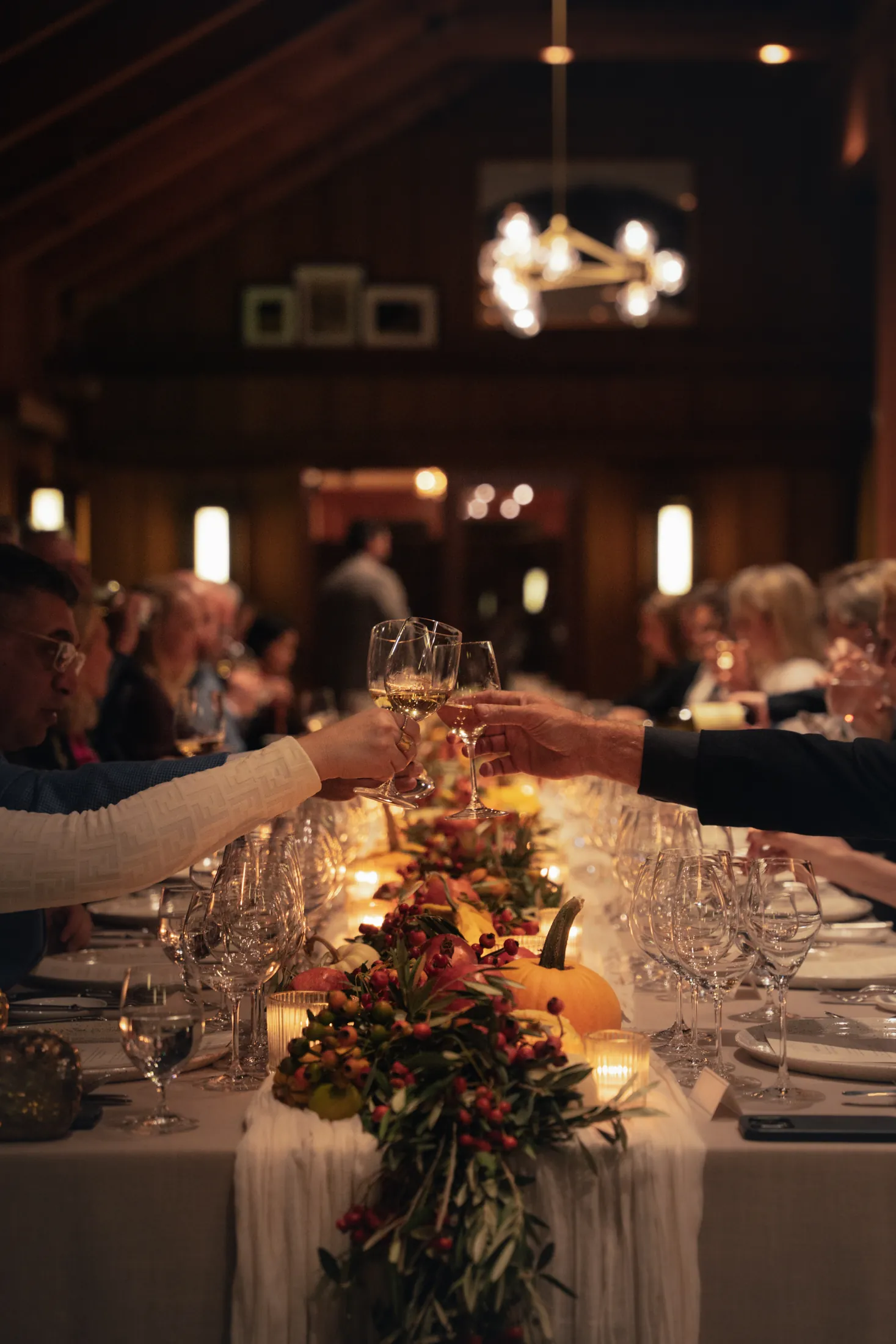 long candlelit dinner table with guests toasting