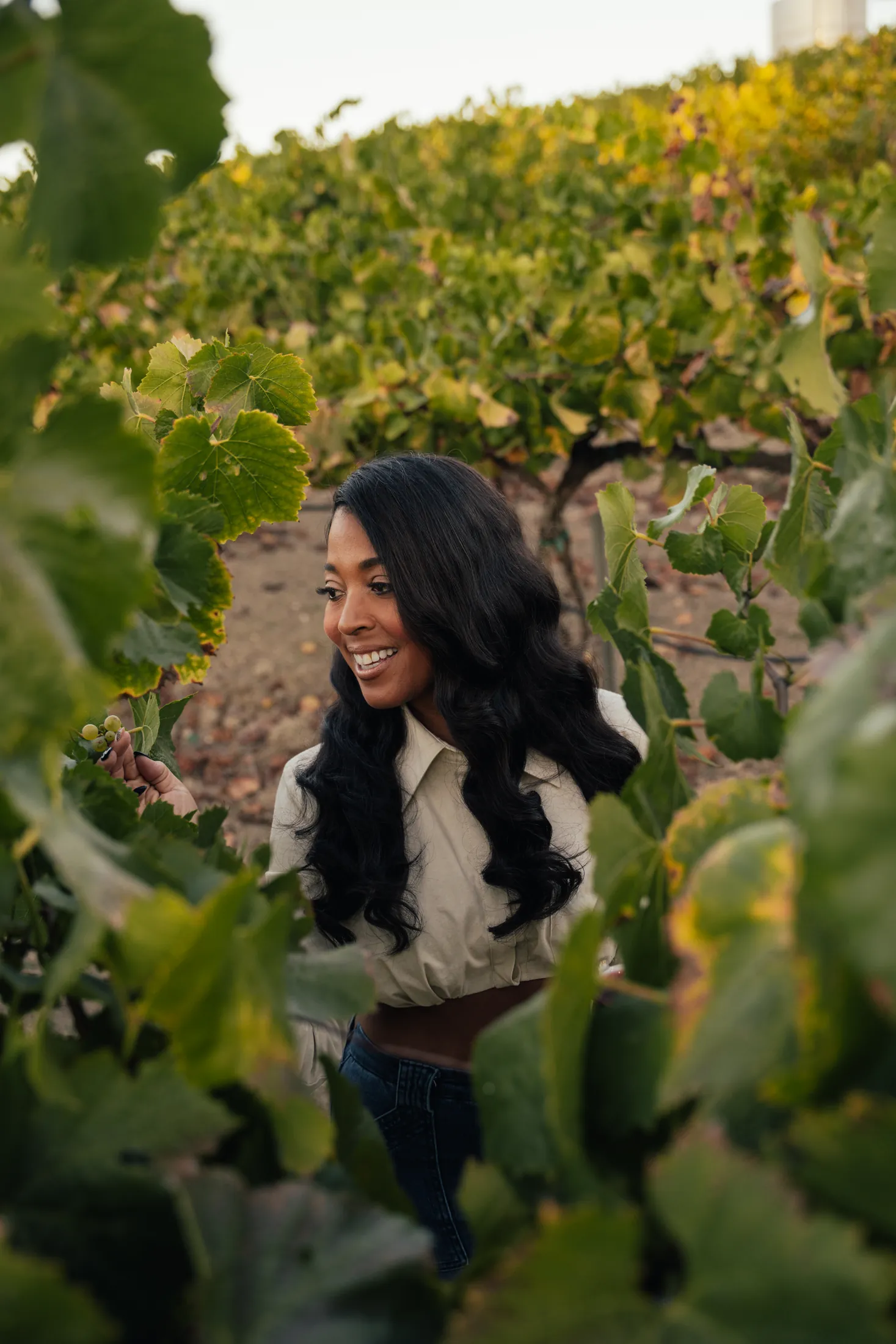 woman smiling among grapevines